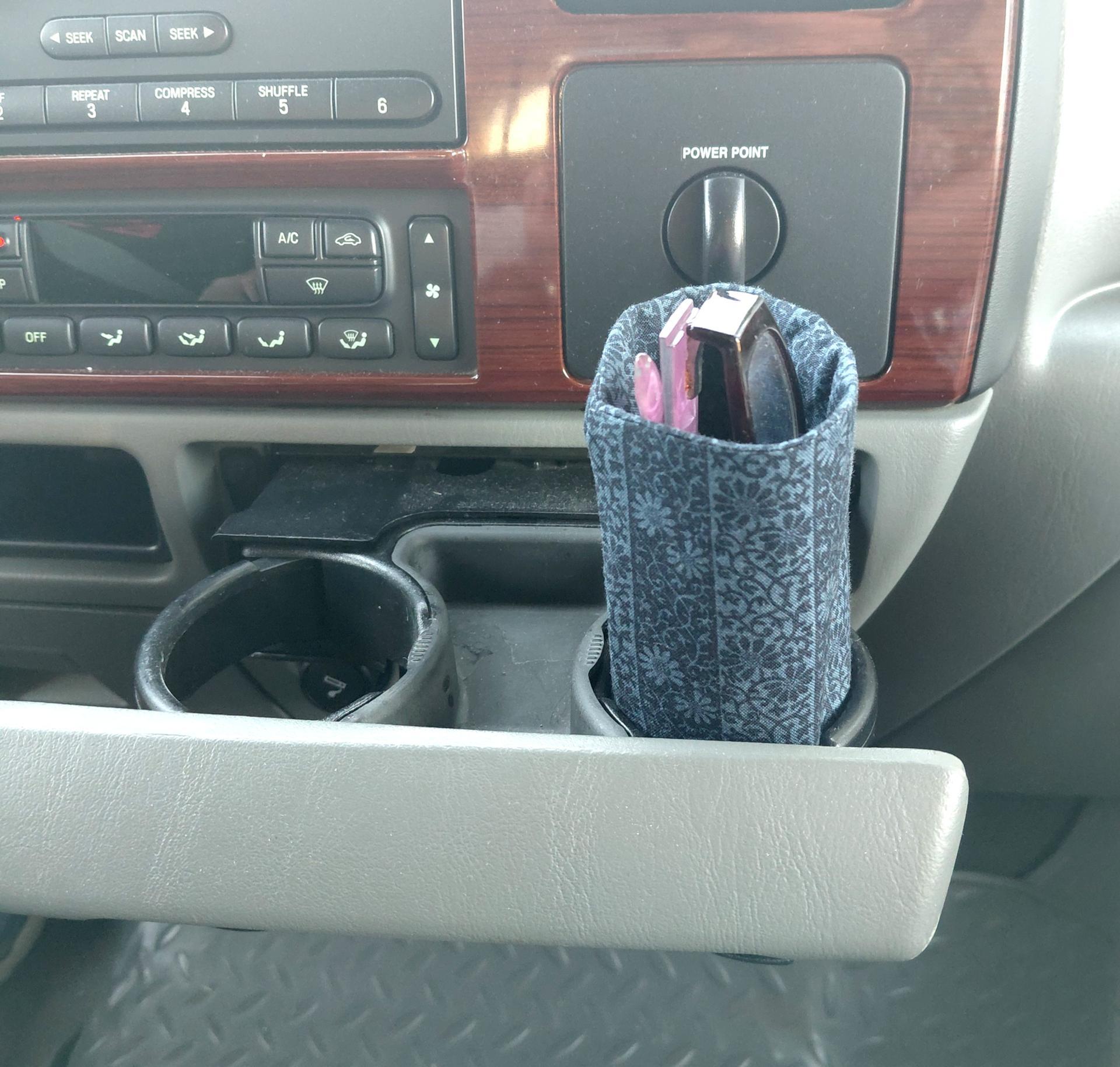 Dark blue upright weighted eyeglasses holder used as a car accessory in a vehicle cup holder.